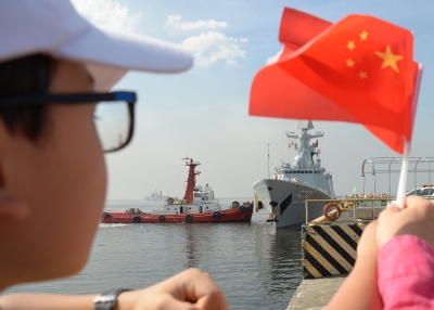 A boy waves a Chinese flag as China's guided-missile frigate Handan (579) prepares to dock at the international port in Manila.